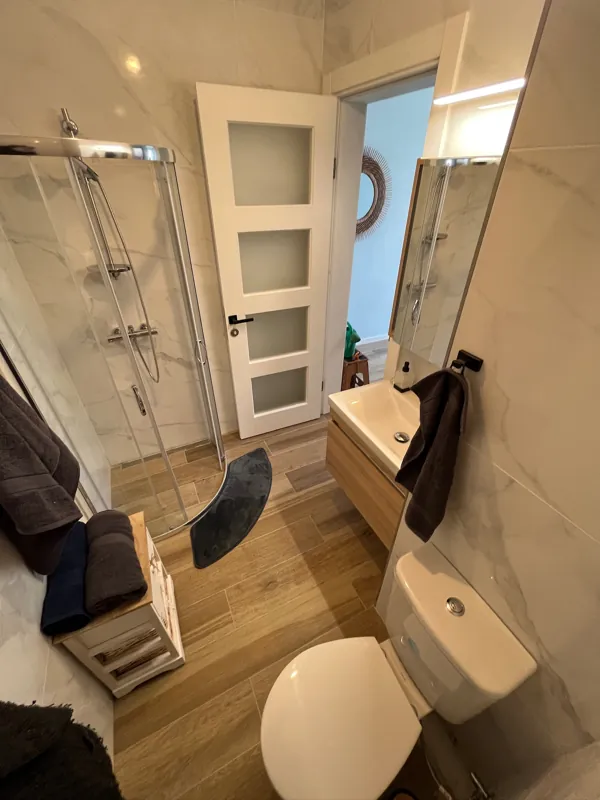 Bathroom with a walk-in corner shower, marble-effect tiles and a wooden vanity